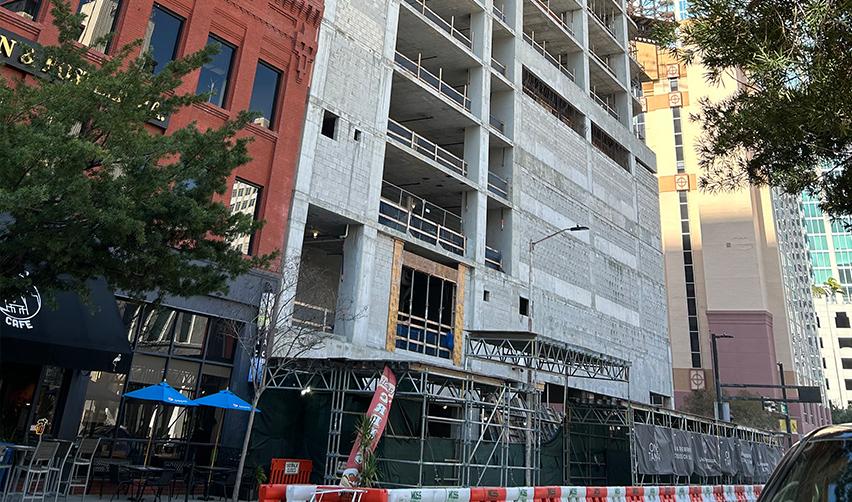 A street-level view of ONE Tampa’s lower floors with active façade work and scaffolding in place, demonstrating continued structural and exterior development for the EB5 project.