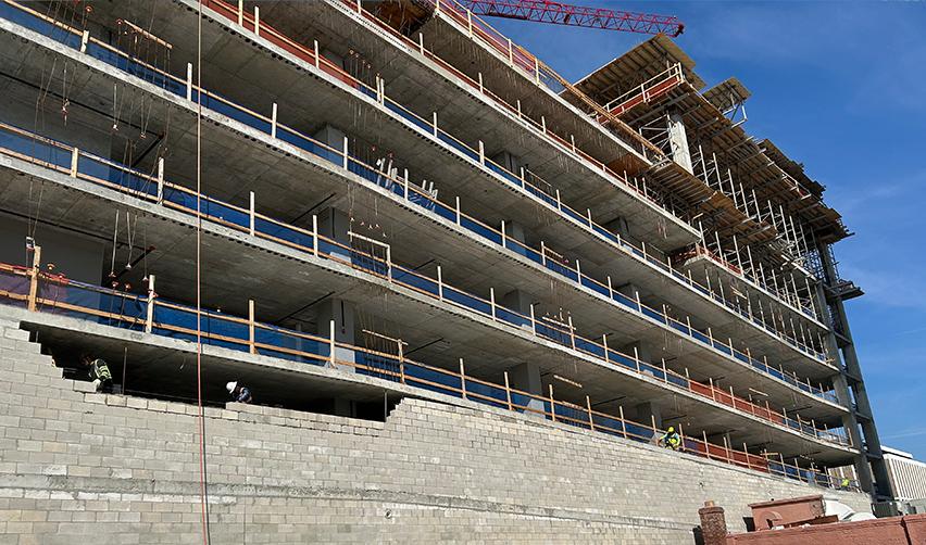 The exterior of ONE Tampa showing multiple finished balcony slabs and ongoing masonry work, capturing significant mid-tower construction progress on the EB5 development.