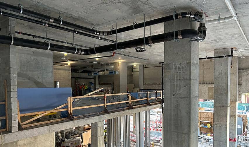 Large mechanical and plumbing lines installed along concrete columns inside ONE Tampa, highlighting advancing interior MEP work within the EB5 project tower.