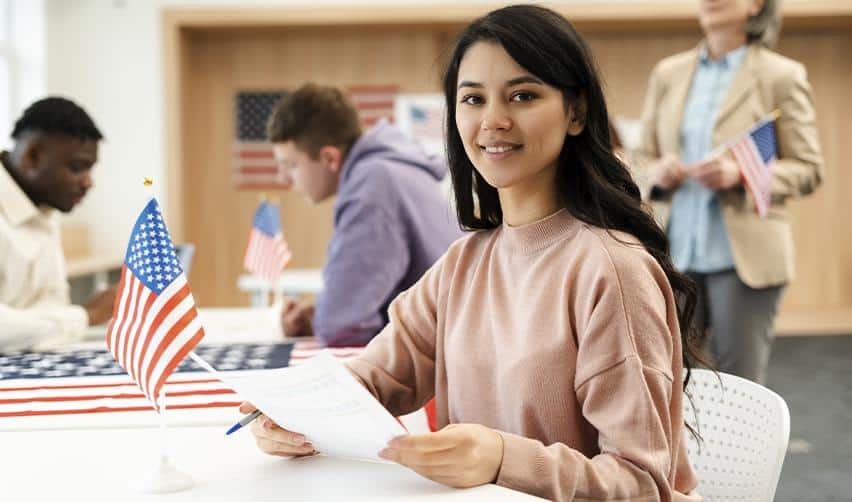 A female EB5 investor reviewing documents at a USCIS-style setting with U.S. flags, symbolizing the EB5 immigrant investor visa application process in 2026.
