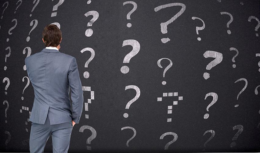 A business professional facing a wall of question marks, illustrating uncertainty and the need for education before committing to an EB5 investment.